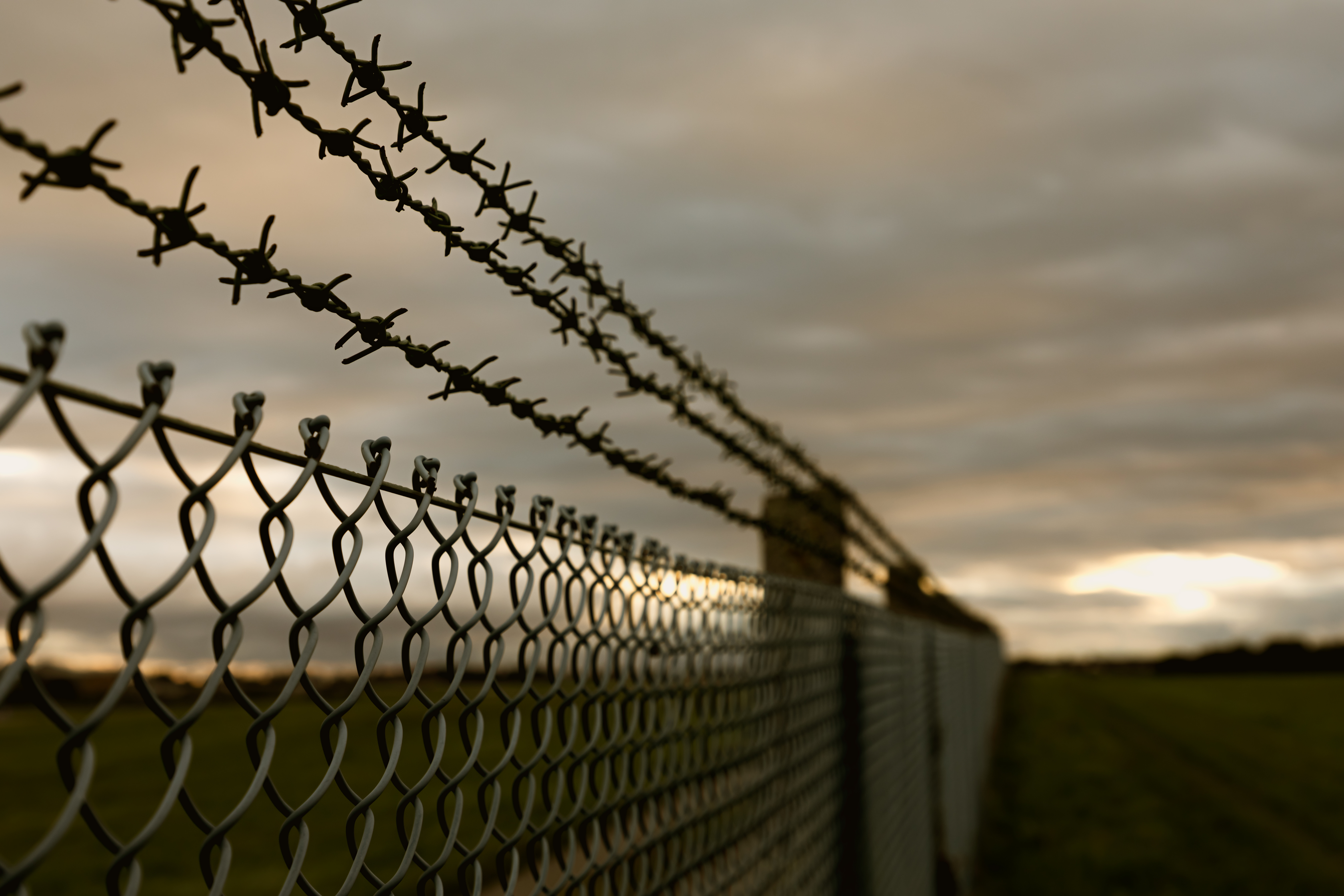 A Black and white image showing a child near a fence with sunlight in the background, symbolizing hope and freedom beyond harmful narratives.
