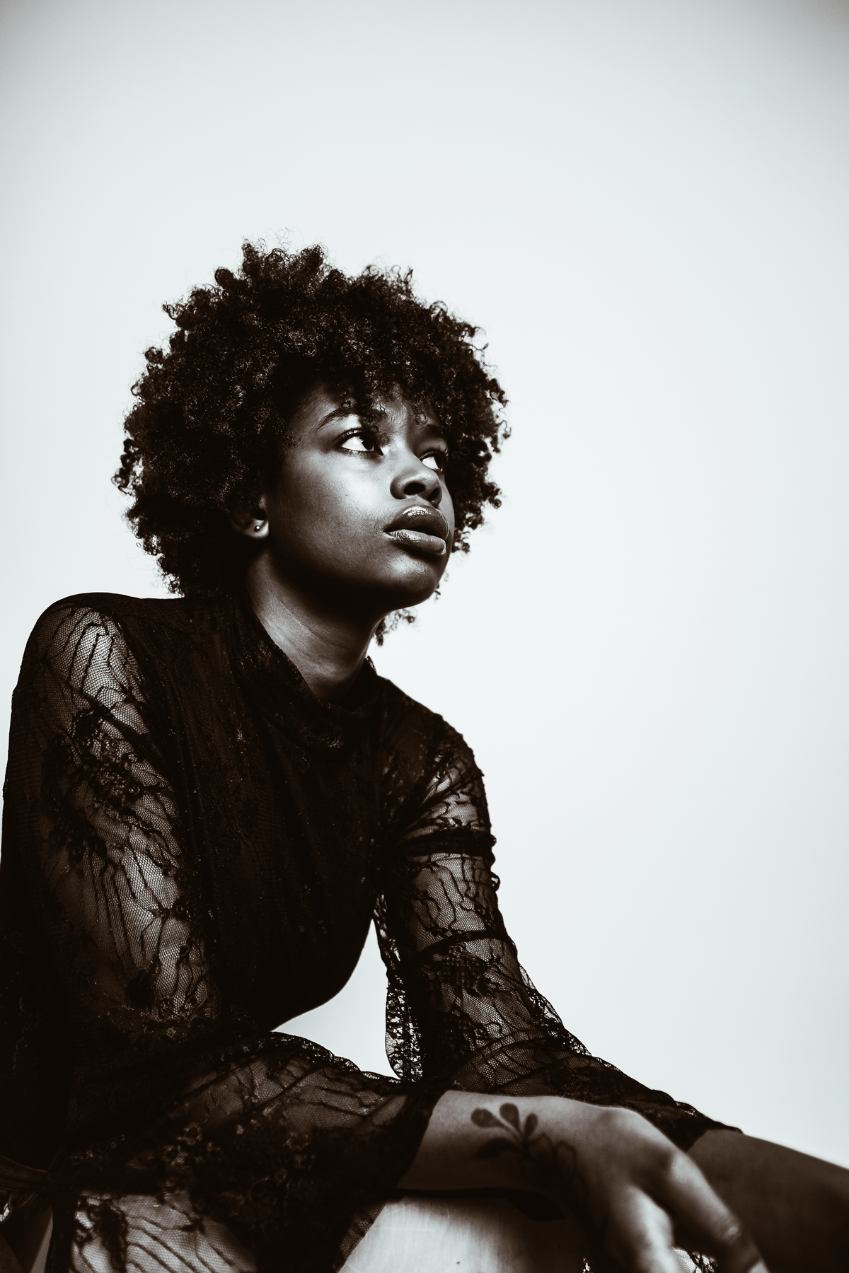 Black woman in a reflective pose against a clean light background